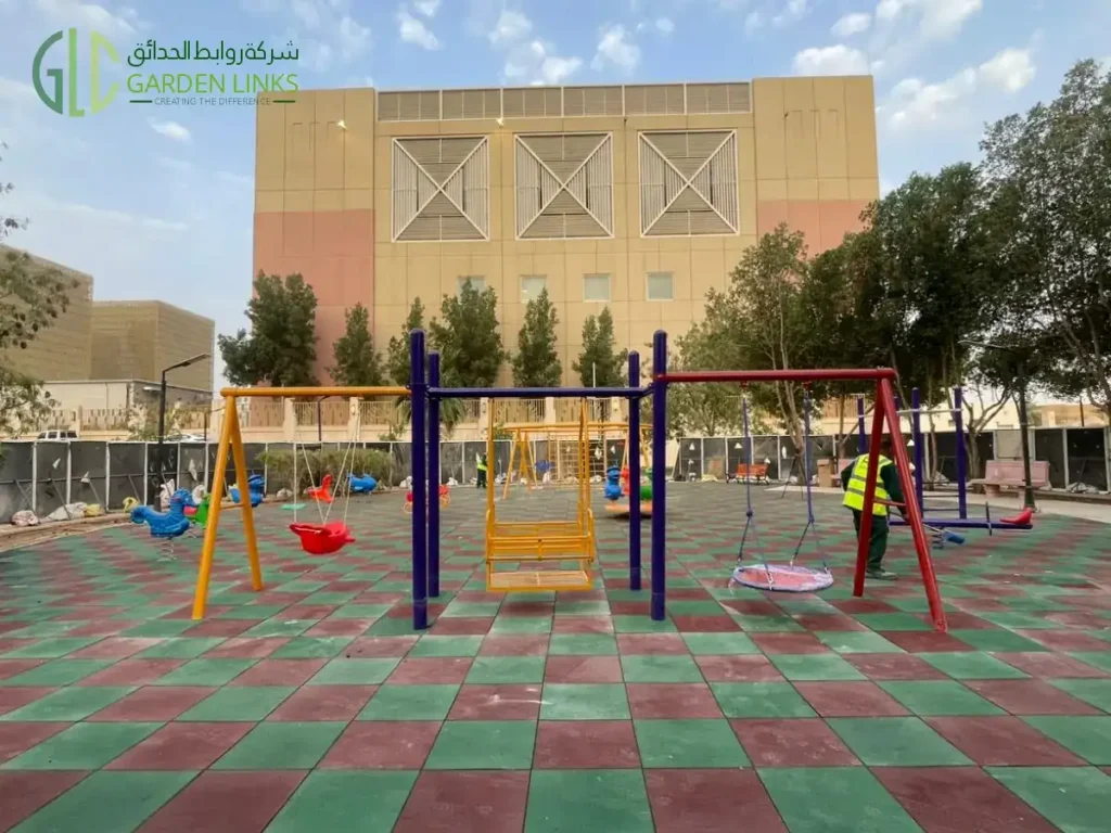 معدات ألعاب خارجية متعددة المراجيح مُثبتة في الرياض، مع بلاطات مطاطية للسلامة، وإطار سلم أصفر، وإطار مراجيح أحمر، ومقعد مرجيحة مسطح، ومنطقة لعب أطفال مفتوحة.
