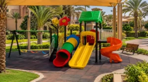 Clean outdoor playground after maintenance with secure equipment, even rubber flooring, open drainage, shade, and landscaped greenery