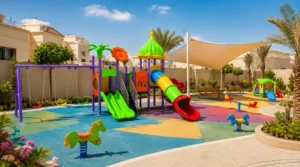 Accessible green playground with step-free pathways, ground-level activity panels, shaded seating, and wheelchair-friendly circulation.