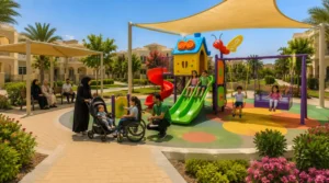 Green swings, slides, toddler equipment, shaded benches, and open pathways arranged with clear movement zones in a Saudi compound.