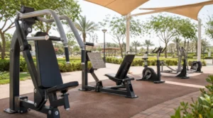 Close view of outdoor gym machines in a Saudi park showing steel frames, powder-coated finish, anchors, and moving parts