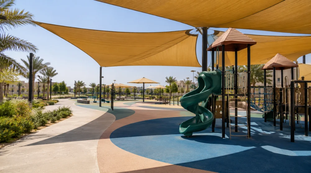 Saudi playground with shaded rubber flooring, lighter colour zones, and exposed areas under strong midday sunlight