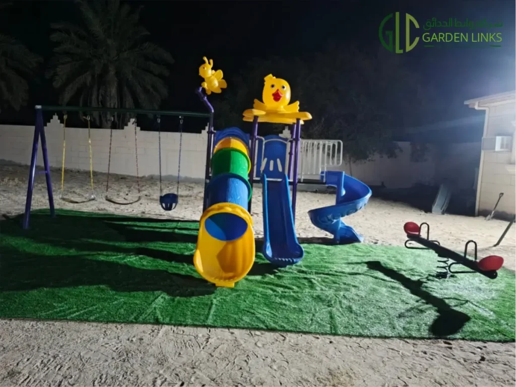 Outdoor playground equipment installed by Garden Links in As Sarrar, Saudi Arabia, featuring a multi-play structure, swings, seesaw, and artificial grass safety surfacing.