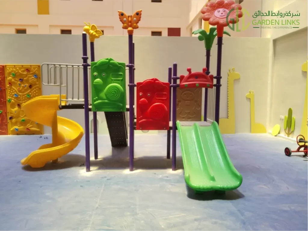 Colorful indoor playground structure featuring green and yellow slides, interactive activity panels, climbing elements, and butterfly and flower-themed decorations.