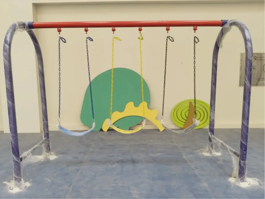 Indoor playground swing set featuring multiple swings with a sturdy metal frame and colorful themed wall decorations.