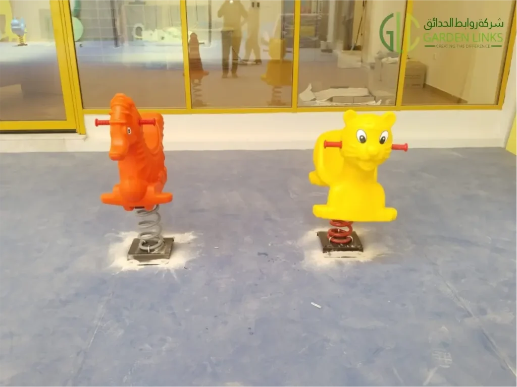 Colorful animal-shaped spring riders, including an orange horse and a yellow character, installed in an indoor children’s playground.