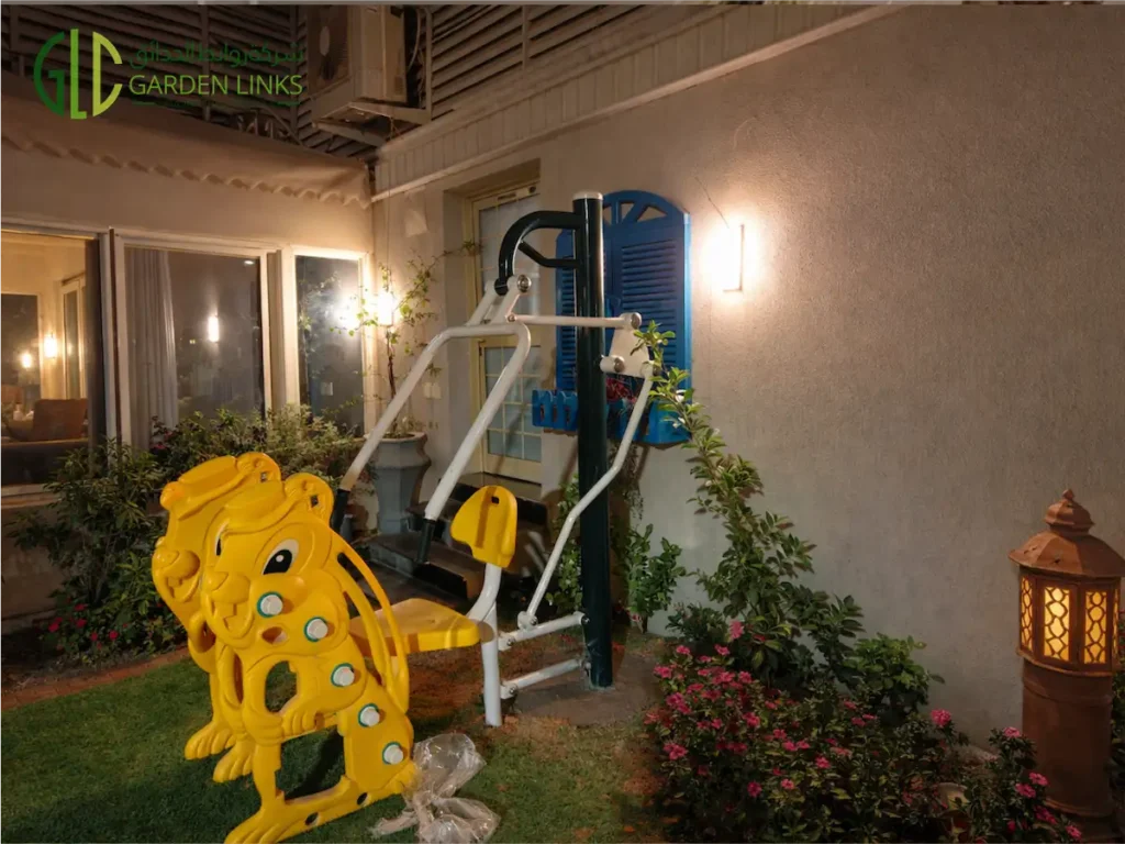 Yellow lion-shaped children's climbing toy installed next to an outdoor chest press fitness machine in a villa garden