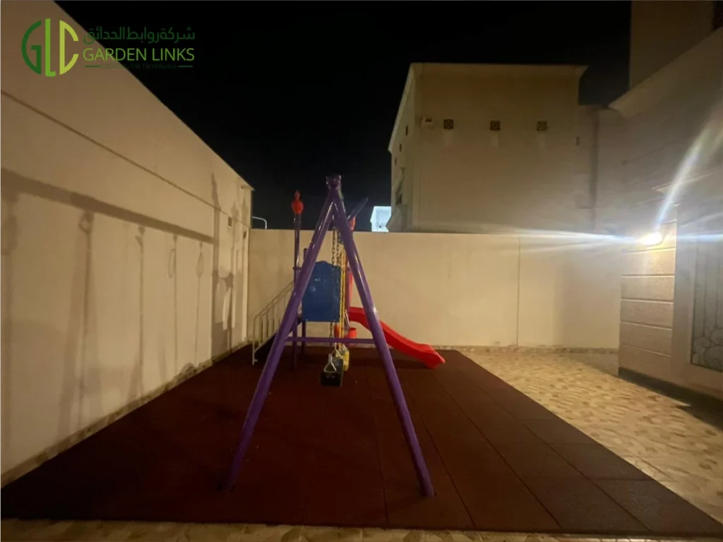 Compact purple swing and red slide combination unit installed on a rubber-tiled rooftop terrace at a Saudi villa