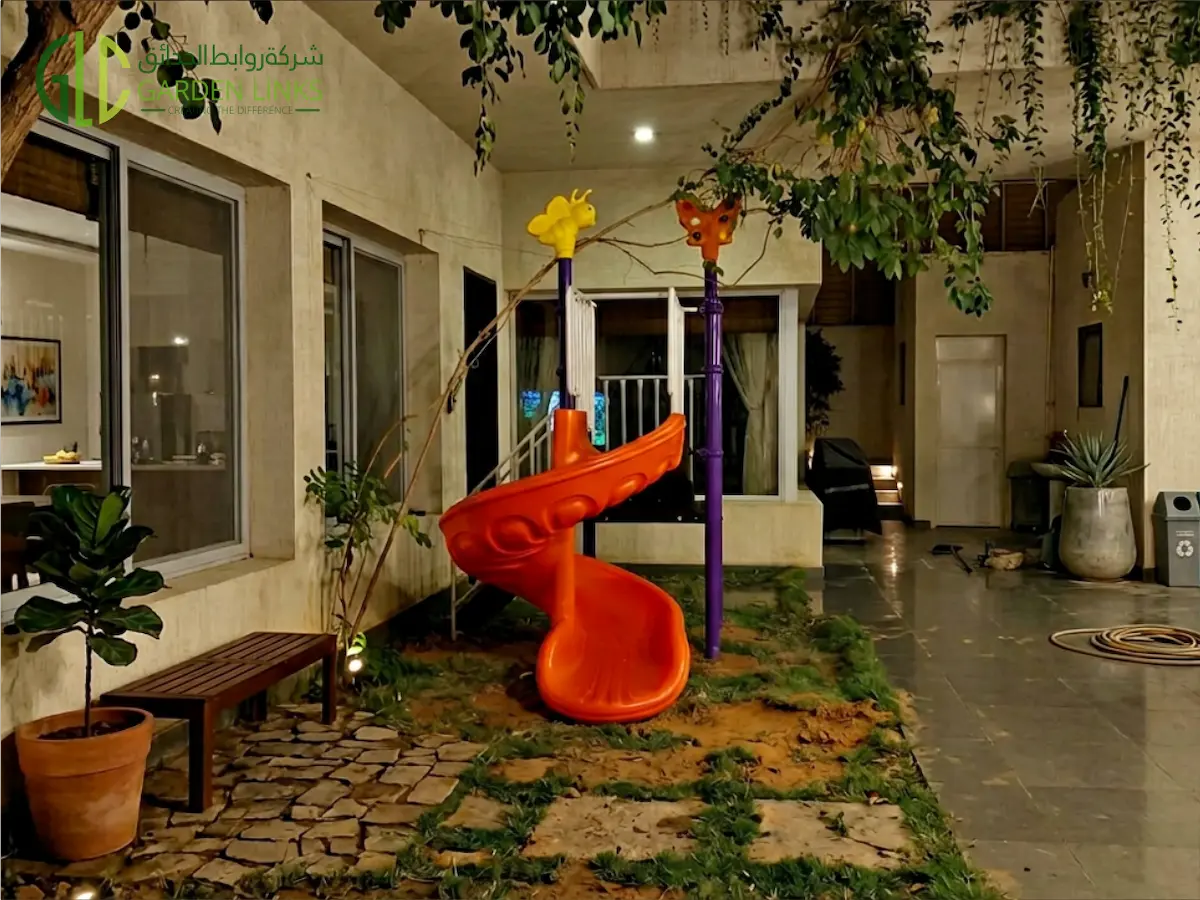 Orange spiral slide with animal-themed poles installed in a shaded villa courtyard in Jeddah, Saudi Arabia