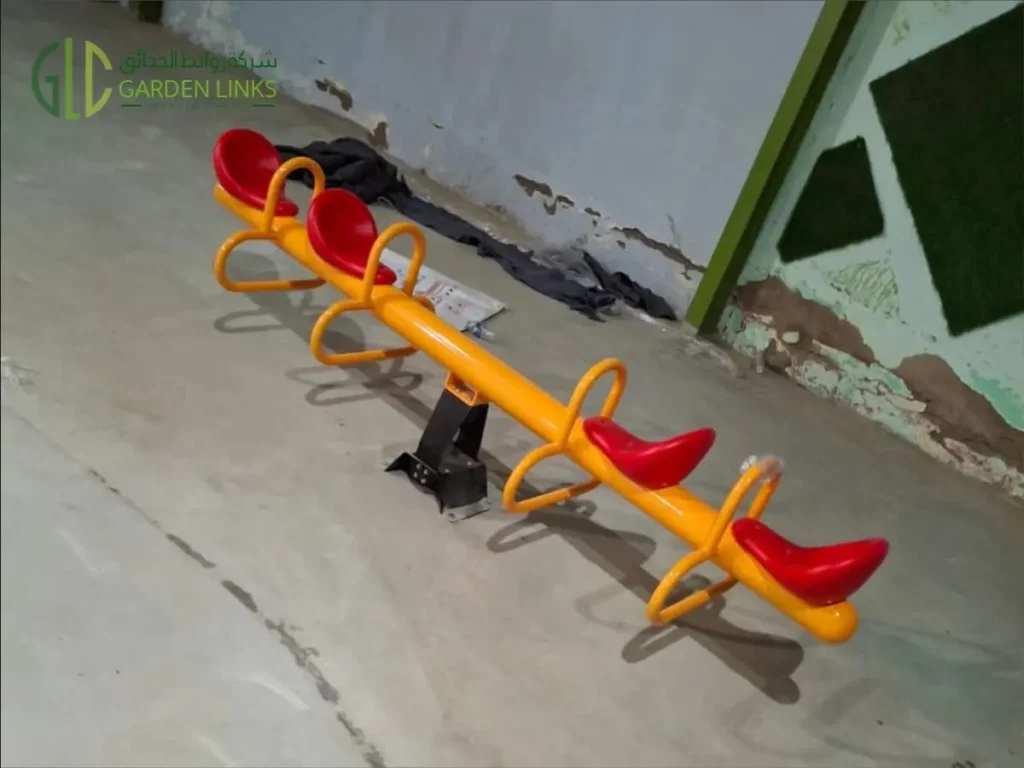 Colorful four-seat outdoor playground seesaw installed in a children's play area in Jeddah, featuring a durable yellow steel frame with red molded seats for safe and fun outdoor recreation.
