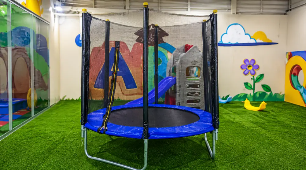 Indoor soft play trampoline with safety net enclosure for active children’s play.