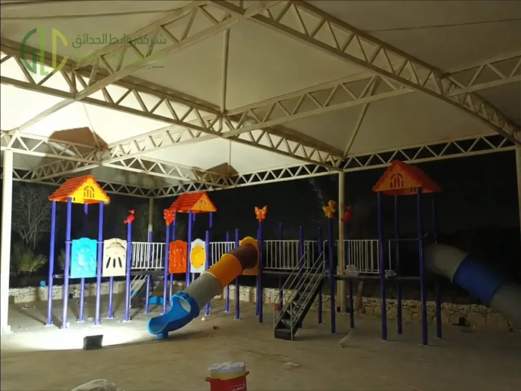 Shaded outdoor playground equipment in Al Kharj with multi-level towers, tube slide, stairs and activity panels.