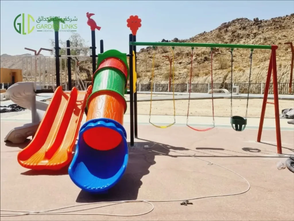 Children’s playground with tube slide, double slide, spiral slide and swing set installed in a public park in Taala, Saudi Arabia.