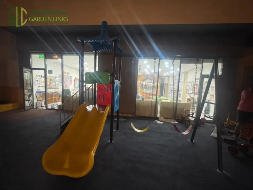 Kindergarten playground installation in Riyadh with straight slide, two-seat swing set, elevated play tower and rubber safety flooring in Al Yasmin.