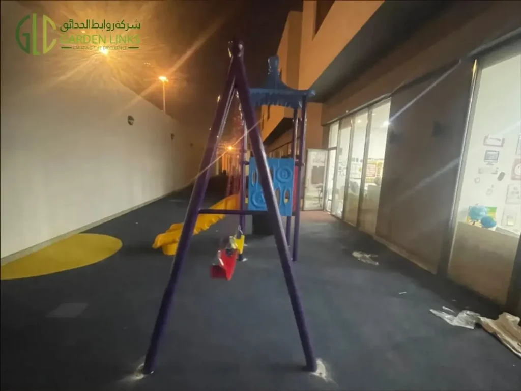 Kindergarten playground installation in Riyadh with two-seat swing set, play structure, slide and rubber safety flooring in Al Yasmin.