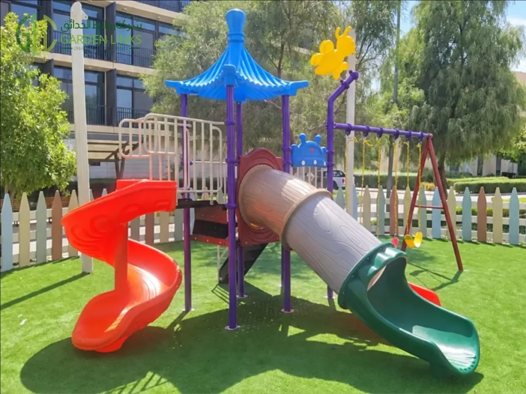 Compound playground installation in Riyadh with spiral slide, enclosed tube slide, double straight slide, three-seat swing set and artificial grass in Ar Rimal.