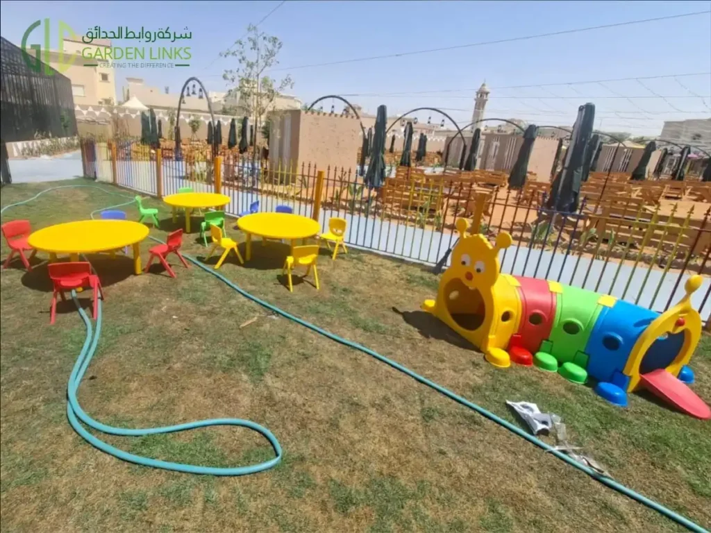 Public park playground in Al Kharj with colorful crawl-through play tunnel, children’s activity tables and chairs.