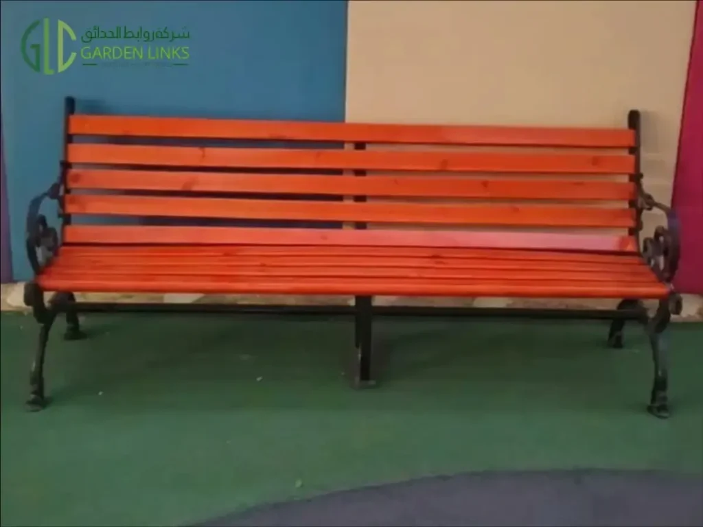 Orange slatted bench with a backrest, black decorative armrests and supporting legs at Beech Hall School.