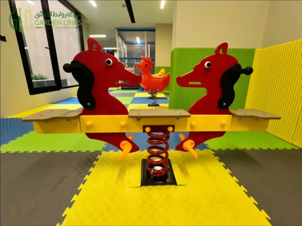 Two-seat spring seesaw with red horse-shaped panels on colorful indoor foam flooring.