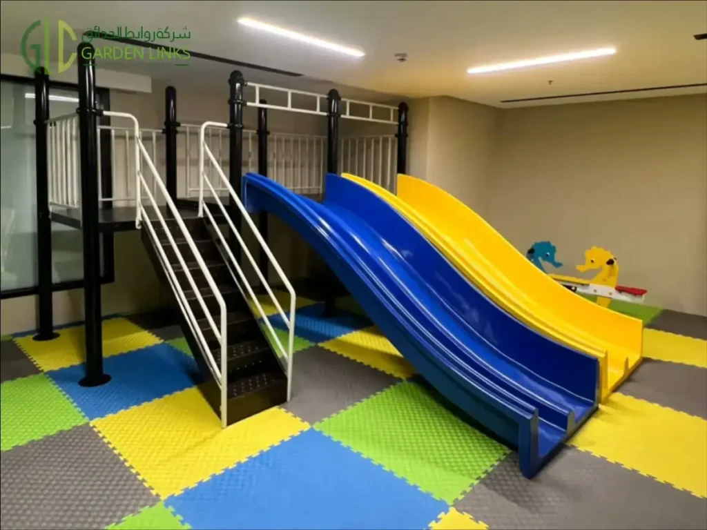 Blue and yellow indoor children’s slides beside a metal access staircase with handrails.