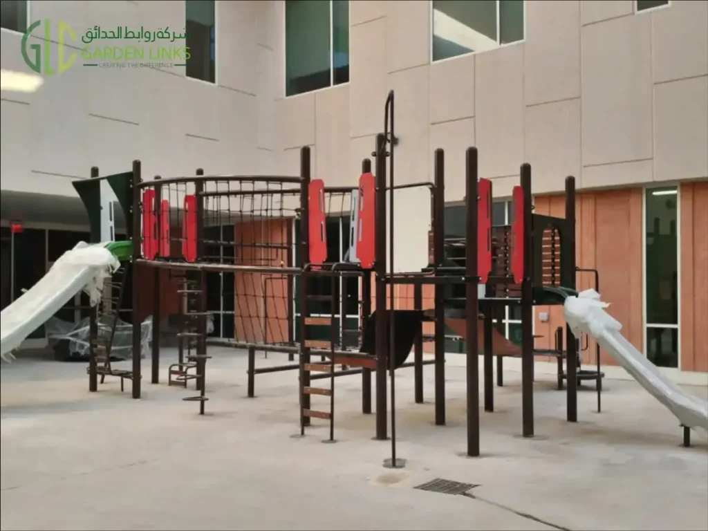 Aramco School Playground Al Ahsa elevated structure with brown posts, access ladders, rope nets, coloured panels and open slides.