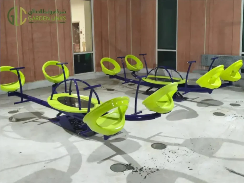 Aramco School Playground Al Ahsa multi-seat spring-mounted equipment with lime-green seats, purple frames and handholds.