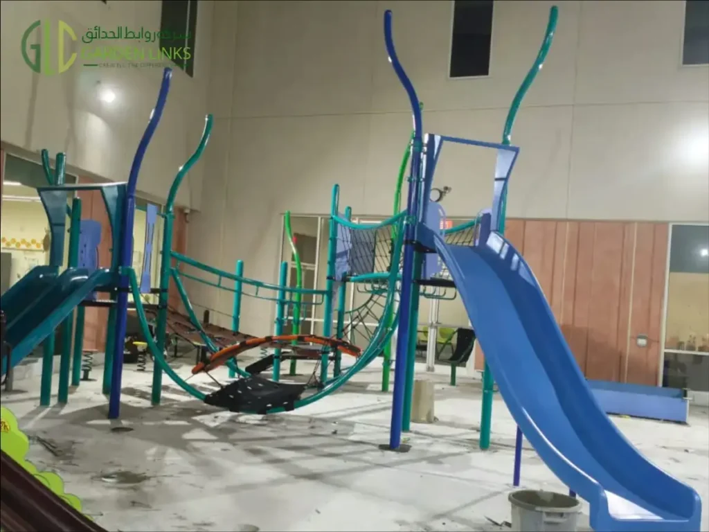 Aramco School Playground Al Ahsa climbing structure with a blue slide, curved posts, rope nets and suspended crossing elements.