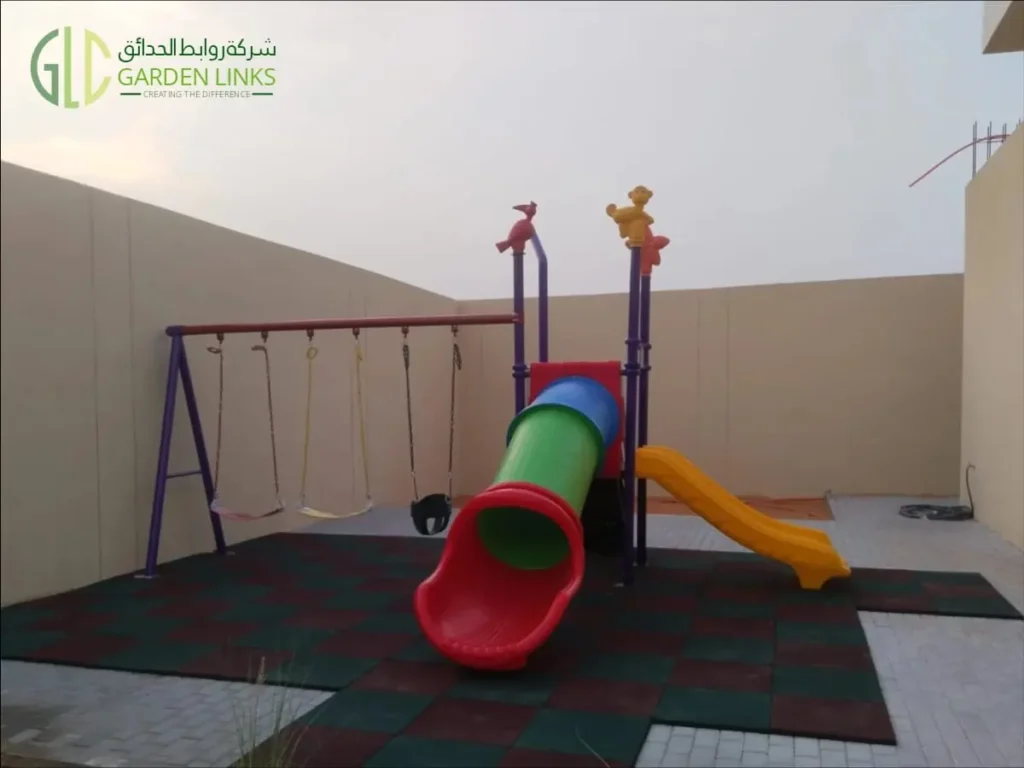 Double and tube slide home playset in Riyadh with a red tube slide exit, yellow double slide, three swings and red and green safety flooring.